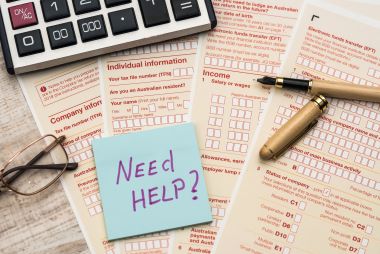 稅務服務 一張寫著需要幫助的貼紙及稅務表格的照片。